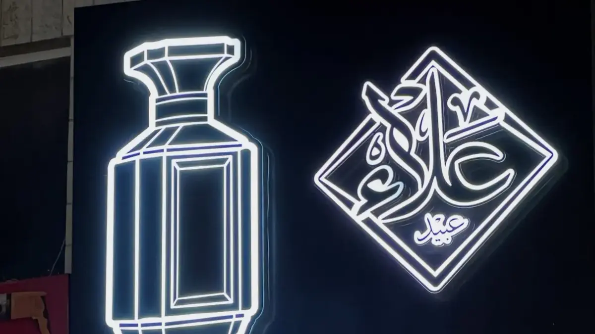 قارمة محل بحروف مضيئة وشعار نيون على واجهة سوداء