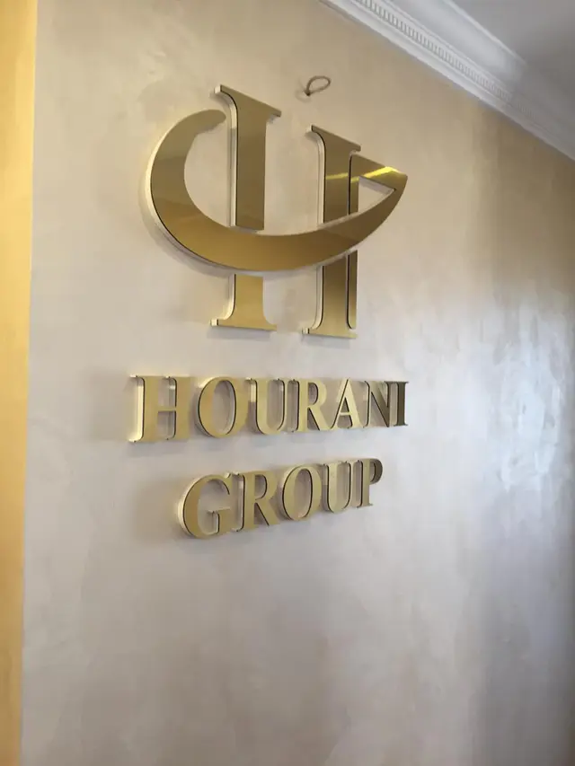 شعار واسم الشركة بحروف ستانلس بتشطيب ذهبي لامع مثبّتة بارتفاع عن جدار الاستقبال.