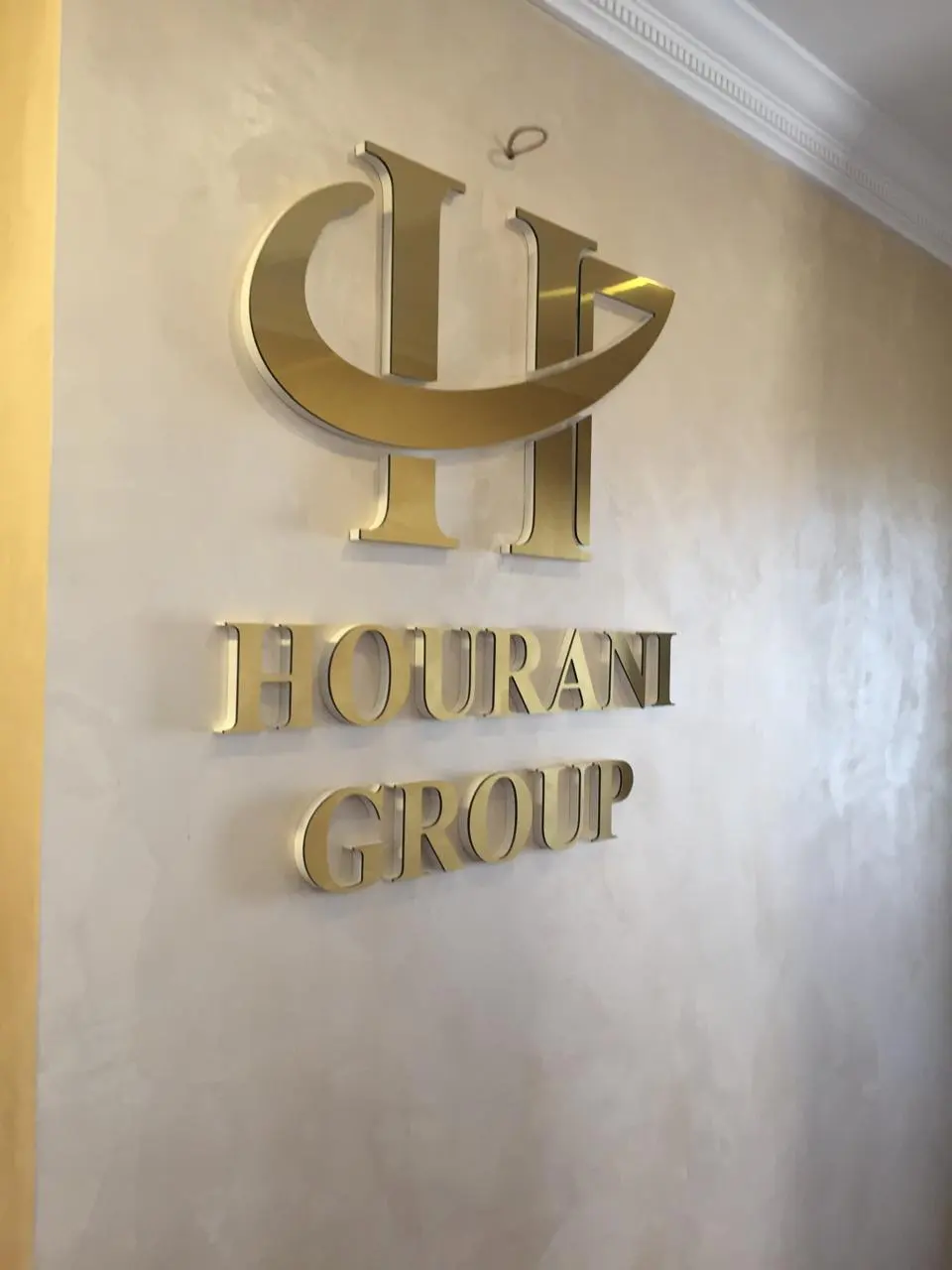 شعار واسم الشركة بحروف ستانلس بتشطيب ذهبي لامع مثبّتة بارتفاع عن جدار الاستقبال.
